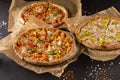 three beautiful colorful juicy different pizzas lie on parchment Royalty Free Stock Photo