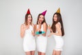 Three beautiful elegant women celebrate holiday party, having fun with cake and drinking cocktails and champagne. Royalty Free Stock Photo