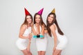 Three beautiful elegant women celebrate holiday party, having fun with cake and drinking cocktails and champagne. Royalty Free Stock Photo