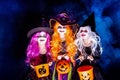 Three Beautiful girl in a witch costume on a dark background in smoke scaring and making faces Royalty Free Stock Photo
