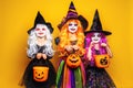 Three Beautiful girl in a witch costume on a yellow background scaring and making faces Royalty Free Stock Photo