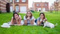 Three beautiful girlfriends are resting lying on the lawn in the countryside. Caucasian women and dog on a picnic Royalty Free Stock Photo