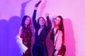Three beautiful girls are dancing in neon. An incredibly fun party with girls in shiny dresses, they celebrate the holiday, smile Royalty Free Stock Photo