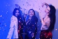 Three beautiful girls are dancing in neon. An incredibly fun party with girls in shiny dresses, they celebrate the holiday, smile Royalty Free Stock Photo