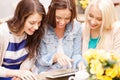 Three beautiful girls looking at tablet pc in cafe Royalty Free Stock Photo