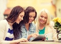 Three beautiful girls looking at tablet pc in cafe Royalty Free Stock Photo