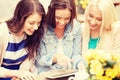 Three beautiful girls looking at tablet pc in cafe Royalty Free Stock Photo