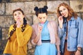 Three beautiful girls models eat lollipops. Girlfriends with different hairstyles and styles. Girls send kisses, wriggles, laugh Royalty Free Stock Photo