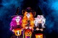 Three Beautiful girl in a witch costume on a dark background in smoke scaring and making faces Royalty Free Stock Photo