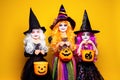 Three Beautiful girl in a witch costume on a yellow background scaring and making faces Royalty Free Stock Photo