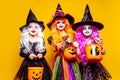 Three Beautiful girl in a witch costume on a yellow background scaring and making faces Royalty Free Stock Photo