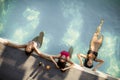 Three beautiful slim women in bikini relaxing and drink cocktails on poolside of a swimming pool Royalty Free Stock Photo