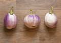 Three beautiful white and purple Bianca eggplants lying on a wood texture tile Royalty Free Stock Photo