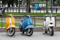 Three beautiful yellow, blue and white retro vespa scooters park