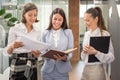 Three beautiful young businesswomen discussing over paperwork in office lobby Royalty Free Stock Photo