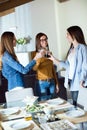 Three beautiful young woman toasting with wine while eating at home. Royalty Free Stock Photo