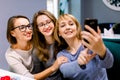 Three beautiful young women enjoying coffee and cake together in a cafe sitting at a table laughing and making selfie Royalty Free Stock Photo