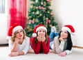 Three beautiful young women lying in front of a Christmas tree Royalty Free Stock Photo