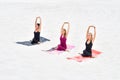 Three beautiful young women sitting in yoga pose Gomukhasana