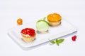 Three beautifully colored cakes on the plate and decoration on white background