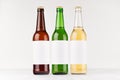 Three beer bottles longneck 500ml different colors with blank white label on white wooden board, mock up. Royalty Free Stock Photo