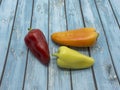 Three bell peppers: red, orange, green, lie on the table Royalty Free Stock Photo
