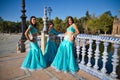 Three belly dancers dressed in light blue leaning on the railing of a bridge. They are talking to each other and looking at the