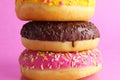 Three Berliners donut pink yellow chocolate with a sprinkle on a pink background leit stack on top of each other with a place for