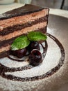 Three berries with green leaf in front of a piece of cake