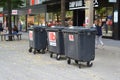 Three big black garbage bins on wheels belonging to a shop standing in the city center of Mannheim