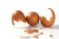 Three big brown eggs is cracking on white background having pieces of egg shell around them, food ingredient for cooking Royalty Free Stock Photo