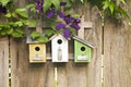 Three birdhouses on old wooden fence with flowers Royalty Free Stock Photo