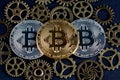 Three bitcoins among copper cog wheels closeup. Cryptocurrency concept Royalty Free Stock Photo
