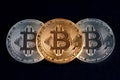 Three bitcoins golden and silver glowing on black background closeup. Royalty Free Stock Photo