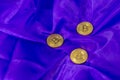 Three Bitcoins on a purple fabric background