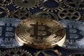 Three bitcoins among various cog wheels extreme closeup on blurred background. Cryptocurrency concept..