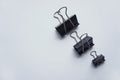 Three black binder clips of various sizes used to staple documents against Royalty Free Stock Photo