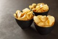 Three black bowl with potato chips on dark background. Royalty Free Stock Photo