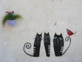 Three black cats with striped tails and red small bird, graffiti on a wall