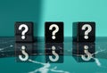 Three black cubes with white question marks are placed on a dark marble surface. Royalty Free Stock Photo