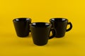 Three black cups on a yellow background. Coffee cups Royalty Free Stock Photo