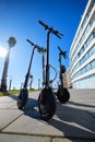 Three black colour electric scooters for adults outdoors on blue sky tropical climate landscape background, no people Royalty Free Stock Photo