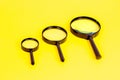 Three black magnifying glass on light yellow background. Royalty Free Stock Photo