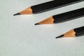 Three black pencils aligned diagonally on a white textured paper. The sharp tips and clean composition create a Royalty Free Stock Photo