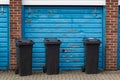 Three black wheelie bins outside the garage of a home awaiting collection