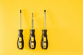three black and yellow screwdrivers on a yellow background with space for text. Tools, construction and workshop, home Royalty Free Stock Photo