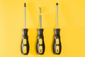 three black and yellow screwdrivers on a yellow background with space for text. Tools, construction and workshop, home Royalty Free Stock Photo