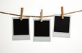 Three blank instant photos hang from a rustic twine string. Wooden clothespins secure empty square frames against a clean white Royalty Free Stock Photo