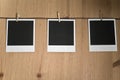 Three blank instant photos hanging on clothesline on wooden background, art concept Royalty Free Stock Photo