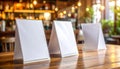 Three blank menu stands on a wooden table in a bar with blurred background empty white Royalty Free Stock Photo